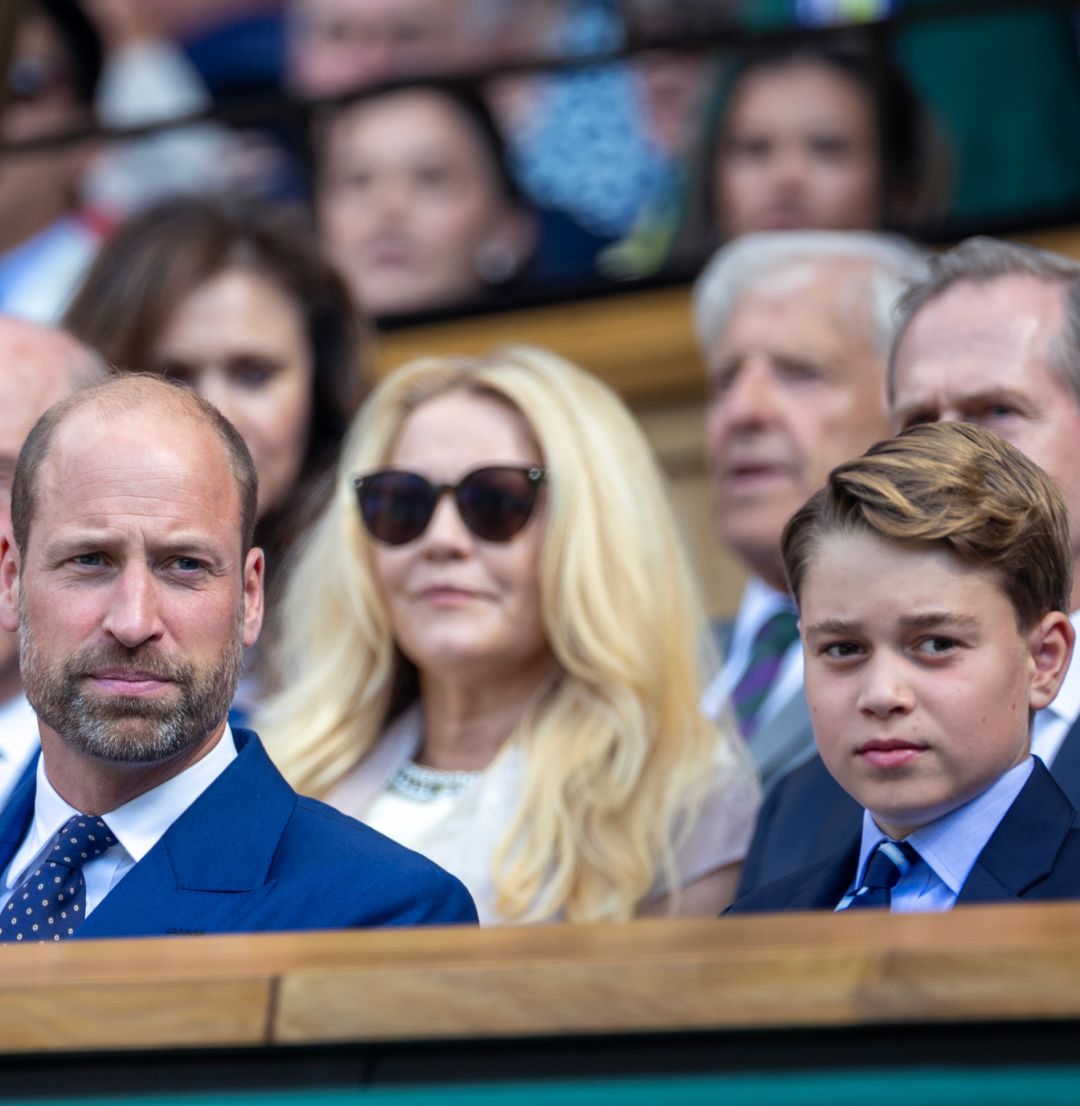 Prince George and Prince William sitting in the stands wearing blue suits at Wimbledon