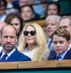 Prince George and Prince William sitting in the stands wearing blue suits at Wimbledon