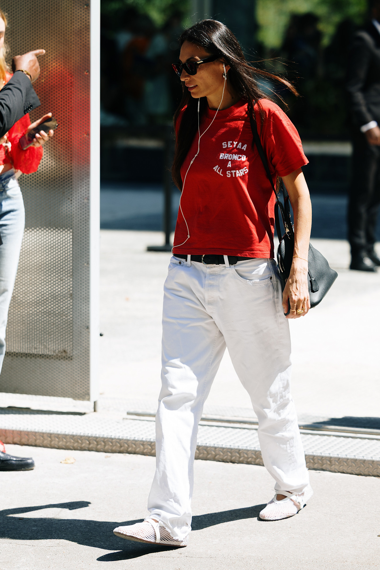 a fashion week attendee wearing sunglasses, red t-shirt, and white jeans