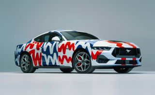 Photograph of the 60th year anniversary celebratory Mustang collaboration with Haus of Thrills. Front on view of white Mustang with colourful lines in white, red and blue with an occasional blue background.