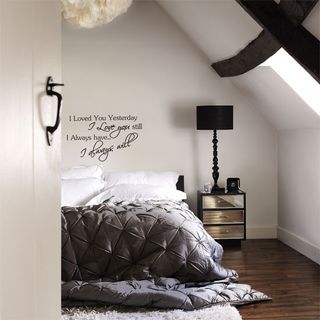 Attic room with bed wooden flooring and white walls