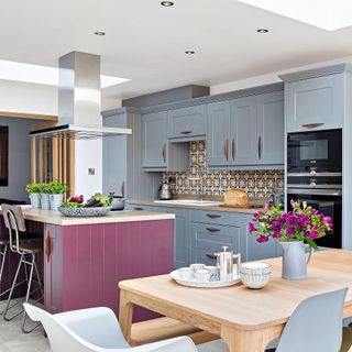 kitchen area with grey kitchen units and pink counter with wooden countertop and dining table with chair