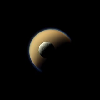 Saturn's largest and second largest moons, Titan and Rhea, appear to be stacked on top of each other in this true-color scene from NASA's Cassini spacecraft released on Dec. 23, 2013. The north polar hood can be seen on Titan appearing as a detached layer at the top of the moon on the top right. This view looks toward the Saturn-facing side of the smaller Rhea.
