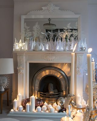 White fireplace, with lit candles and white paper decoration