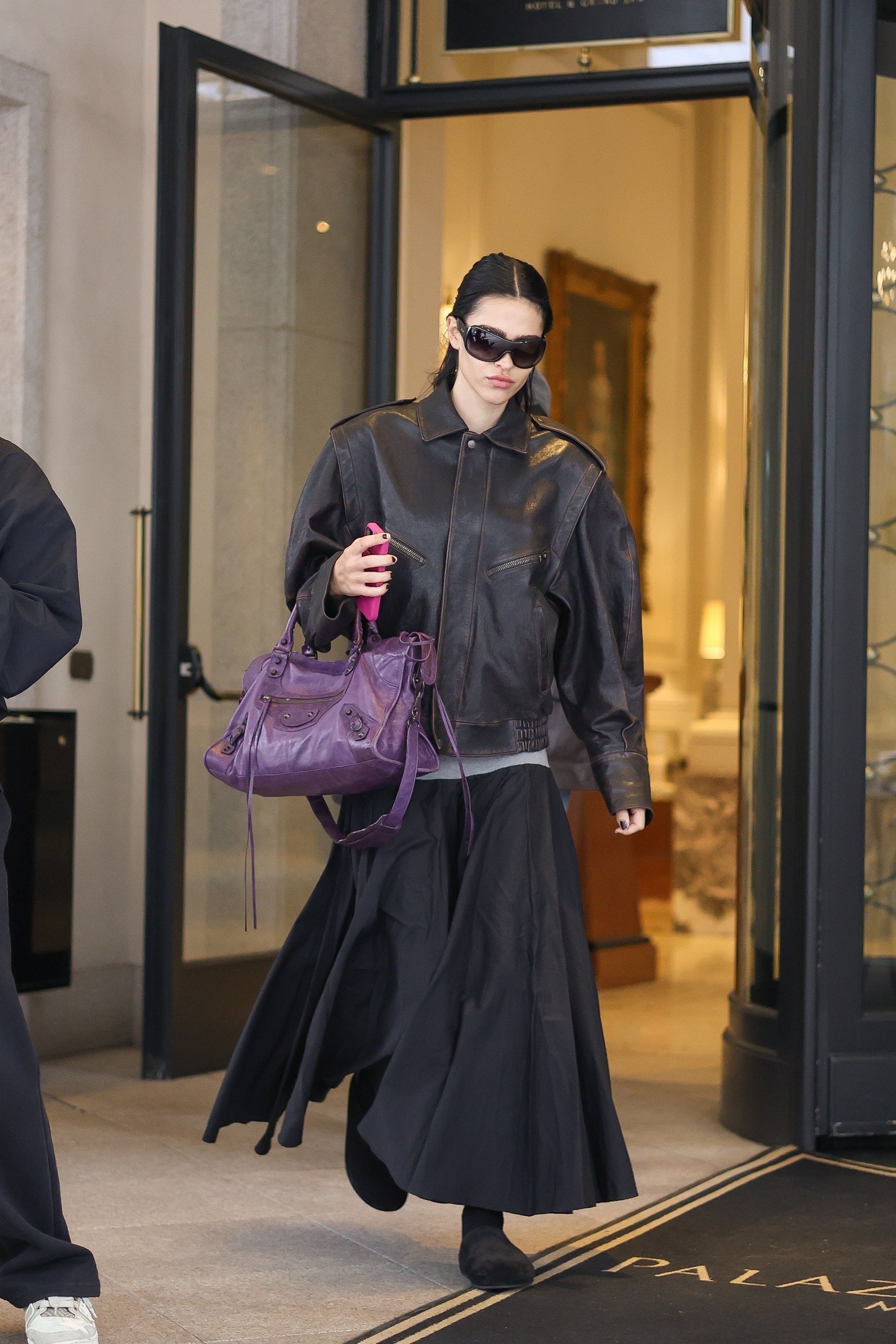 Amelia Gray wears a Balenciaga bag with a midi skirt and clogs at Milan Fashion Week.