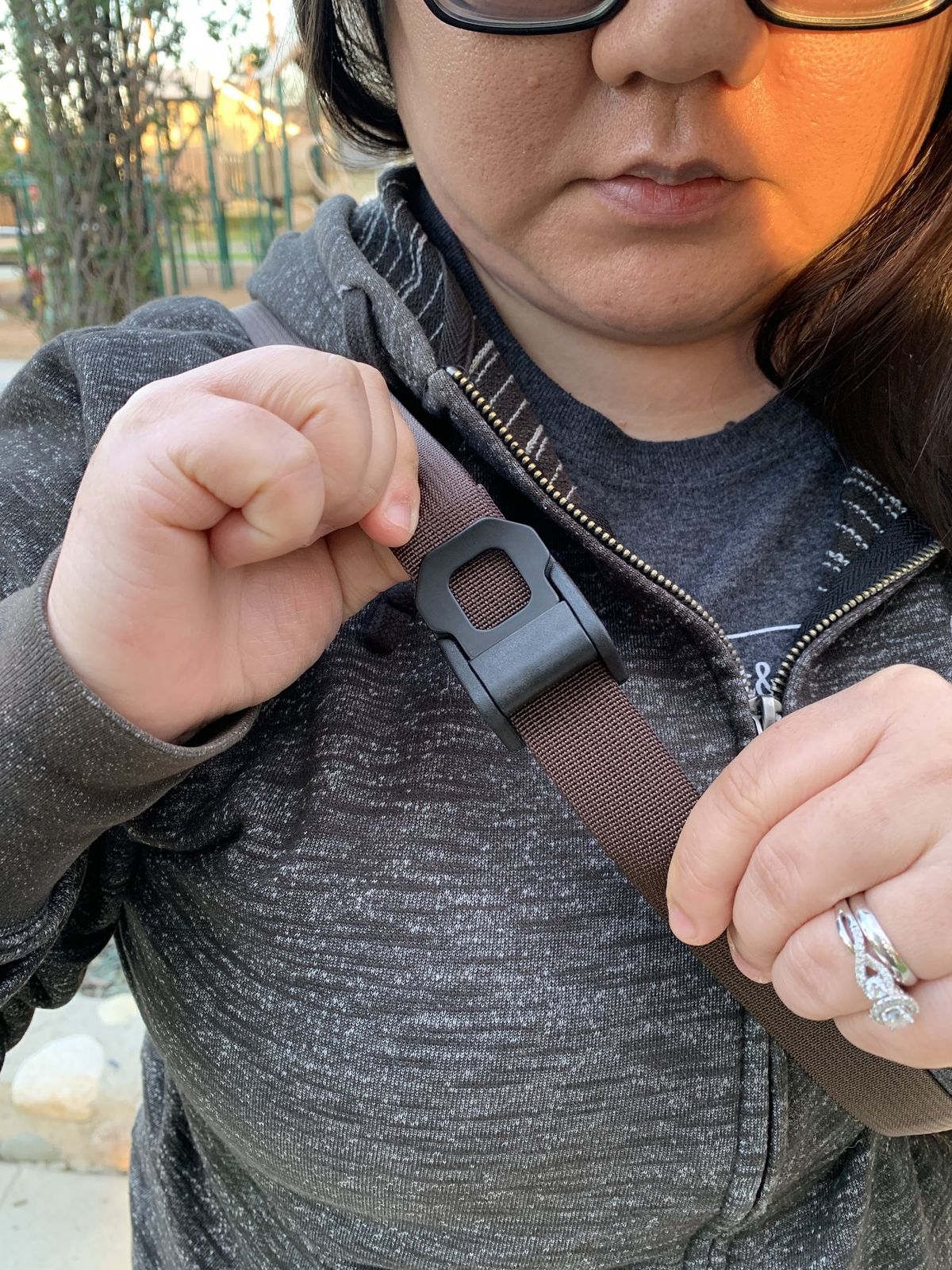 Waterfield Designs Sutter Sling Pouch for Nintendo Switch worn by Christine Chan as she adjusts shoulder strap clasp shut