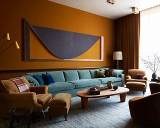 orange painted living room with large blue sofa and curved coffee table on gray rug