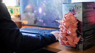 An Avowed mushroom kit growing mushrooms on a gamer's desk while they play.