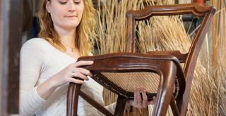 Woman looking at antique chair to demonstrate an essential tip for buying second hand furniture