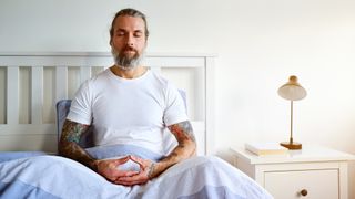 A man meditating in bed