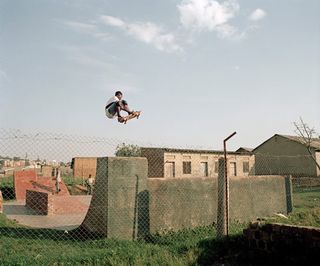 A man in the air on a skateboard above a skate board ramp.