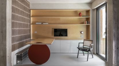 Home office space with oak bookcase and simple desk that slides on a round red wooden wheel