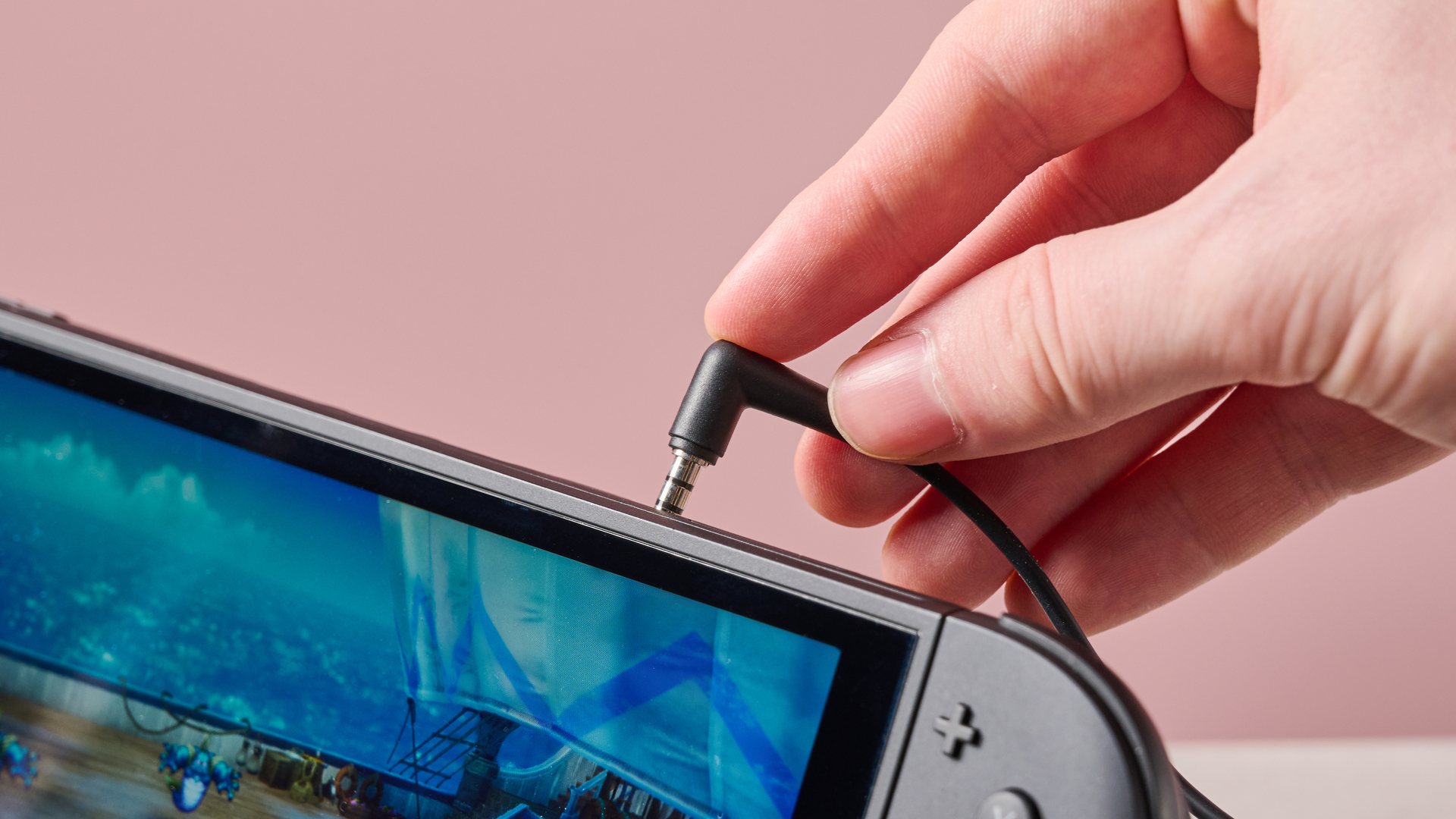 Person inserting PowerA Wired Earbuds for Nintendo Switch 2 into Switch 2 console with Dragon Quest I &amp;amp; II HD-2D Remake on display