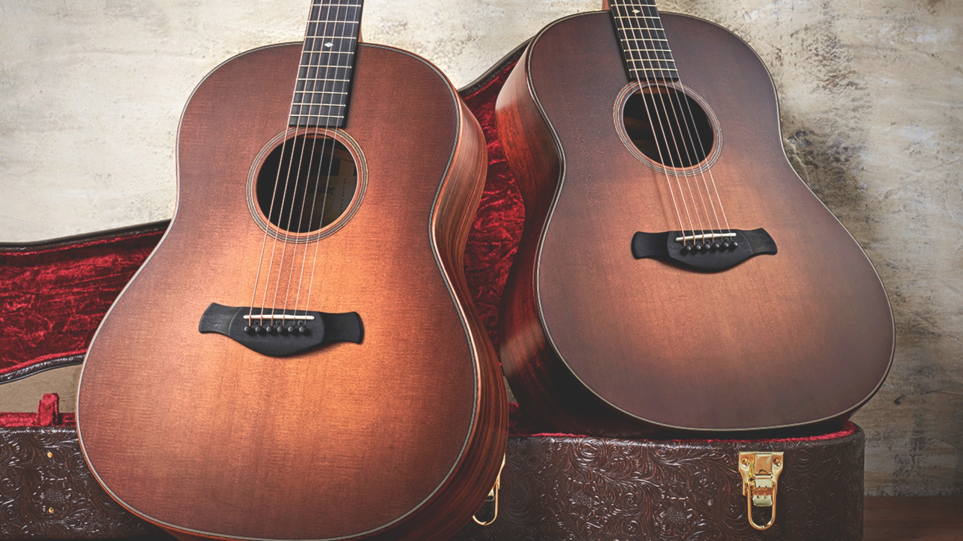 Two Taylor acoustic-electric guitars sitting on top of a hard case