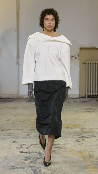 Carven model at the F/W24 show wearing a white blouse, black skirt, and black almond-toe pumps.