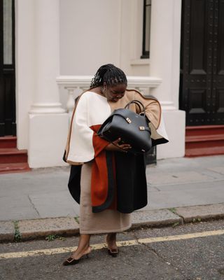 Woman wears patterned dress, black mules and black bag