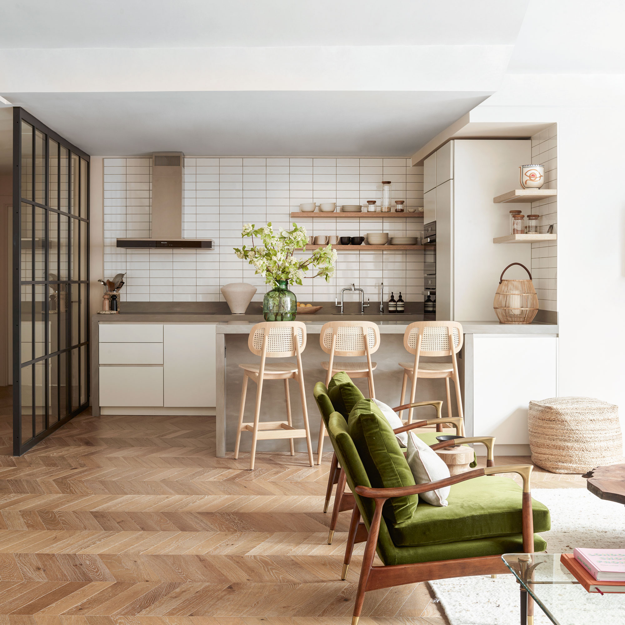 White tiled kitchen with a breakfast bar and green armchairs