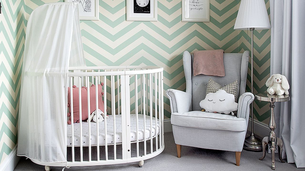 Nursery with green and white zig zag wallpaper and white oval cot