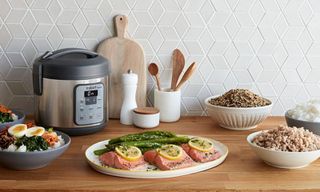 Instant Pot rice cooker and selection of cooked savory dishes on kitchen countertop, counter made from wood, with tiled splashback