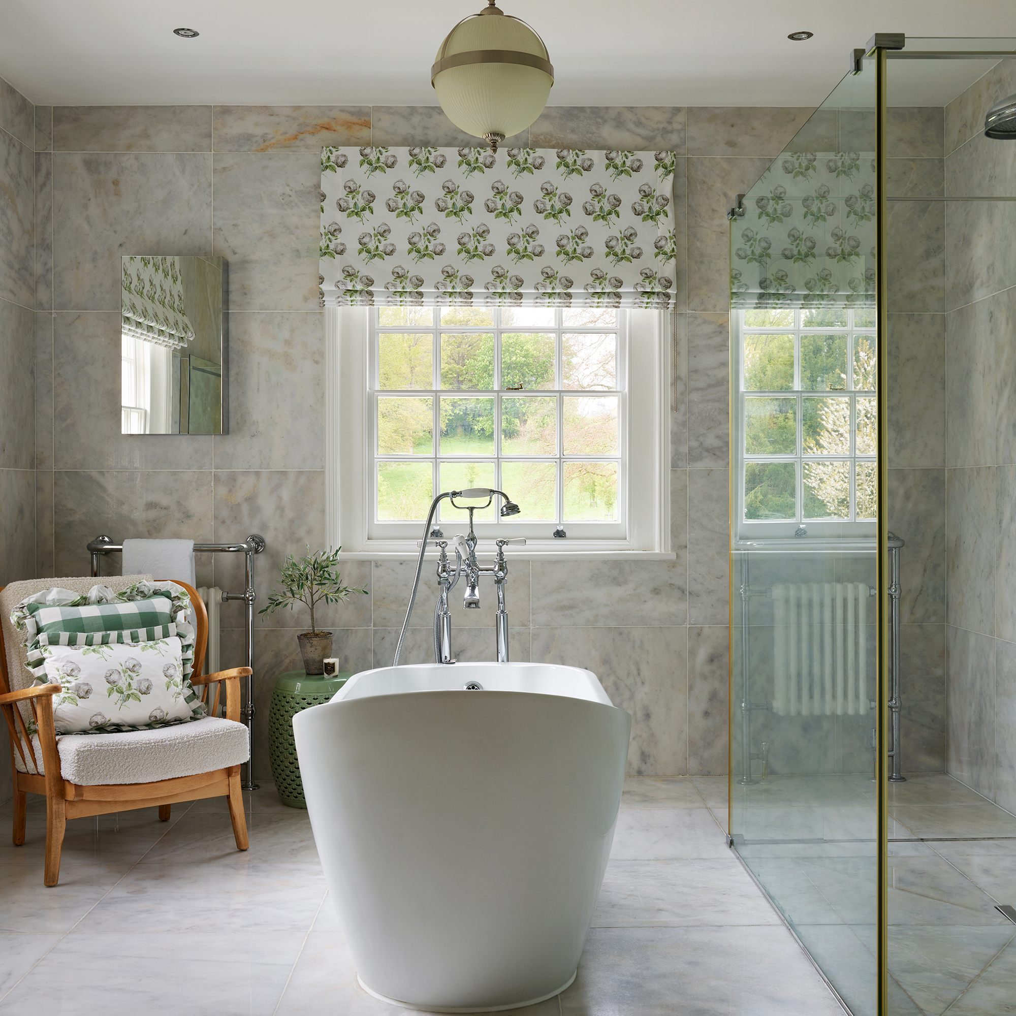 luxurious bathroom with marble tiles, freestanding tub, patterned blinds and large shower enclosure