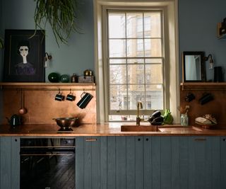small kitchen with dark blue walls, cabinets and copper worktop and splashback