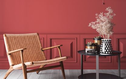 Living room with bright red walls, a rattan chair and coffee table