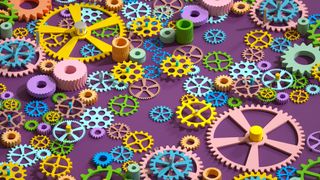 A CGI render of a dozens of multi-colored gears of all different shapes representing open source software, set against a purple background.