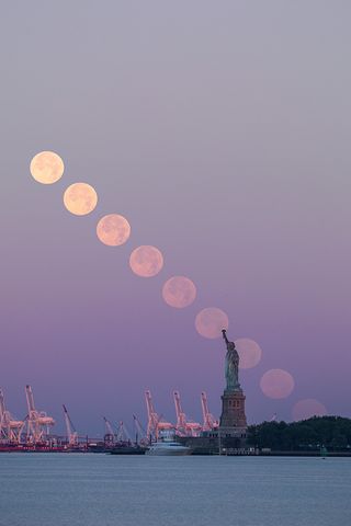 The full Thunder Moon sets behind the Statue of Liberty in New York City in this composite image taken on Sunday morning (July 9).