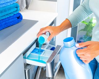 Woman adding liquid detergent to a washing machine