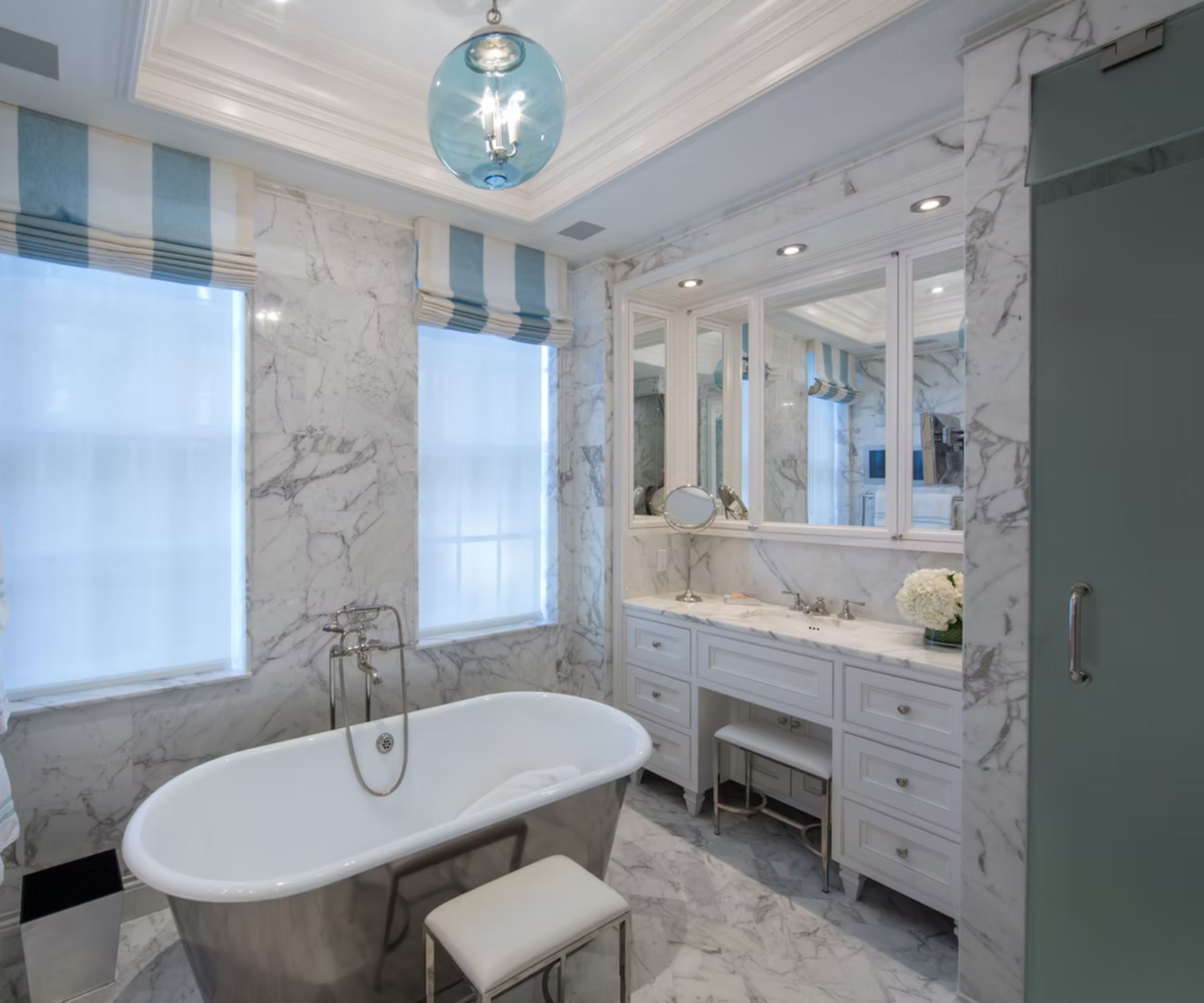 Marble bathroom with a white vanity illuminated by three spotlights