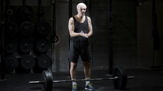 Senior standing near a barbell in a gym