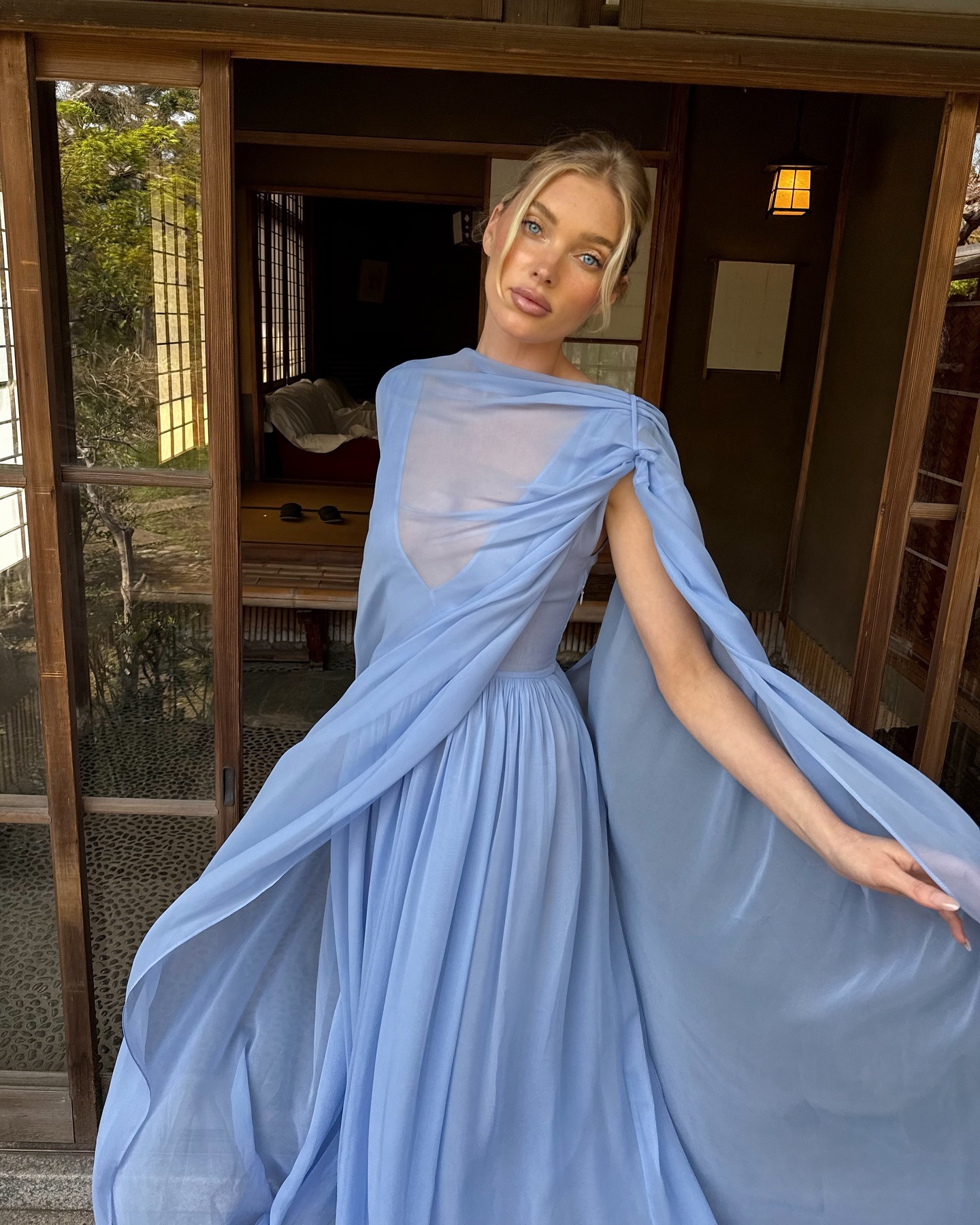 Elsa Hosk wearing a blue dress and her hair in an updo with face-framing pieces.