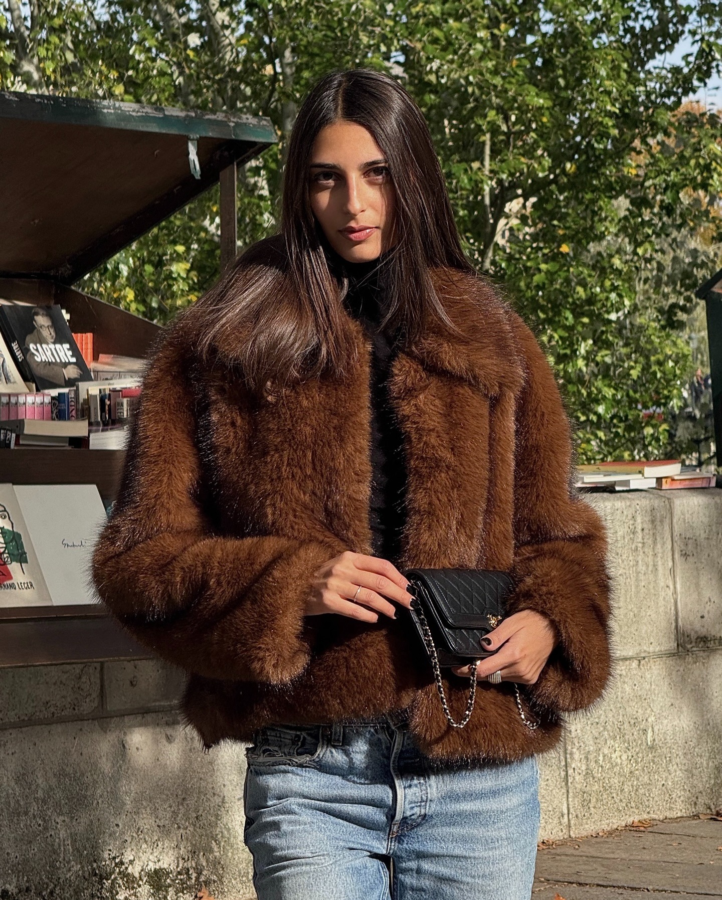A woman in a brown faux-fur jacket and jeans