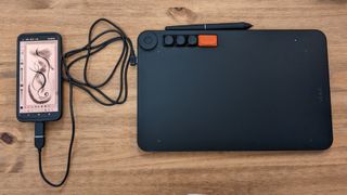 A black Veikk Voila L Pen Tablet sitting on a wooden desk