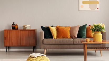 Fall living room in orange, green and brown colours with grey sofa and cushions 