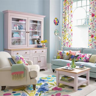 living area with teal wall and pink cabinets and arm chair blue sofa and curtains