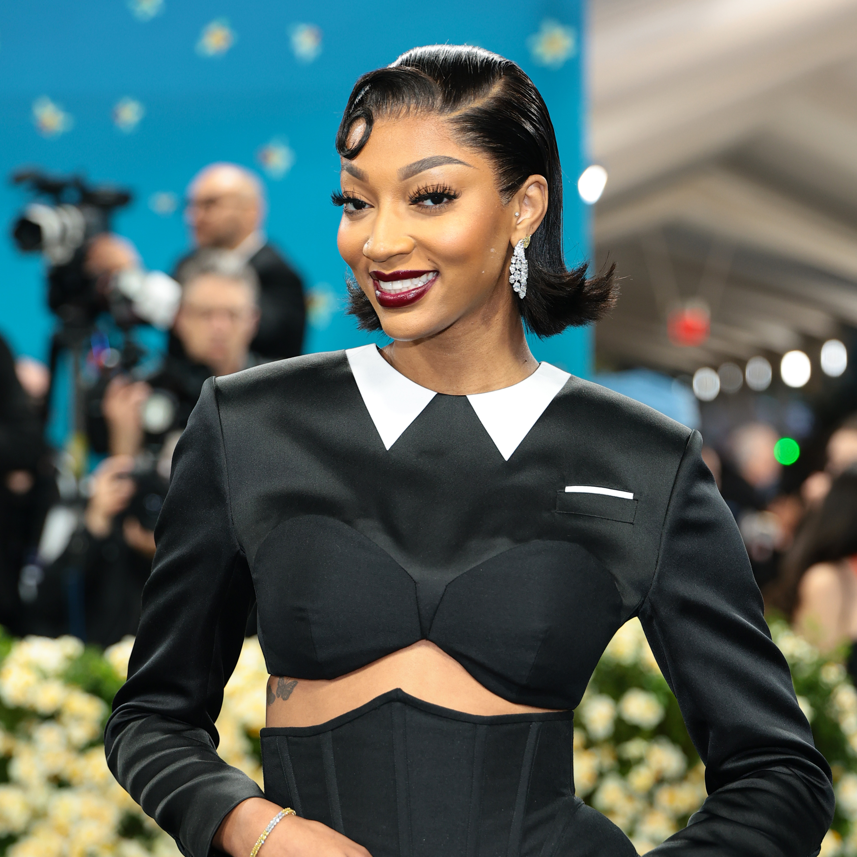 Angel Reese wearing a kiss curl flipped bob and a dark lip color.