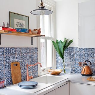 kitchen with kitchen sink wooden chopping board and tiles on wall