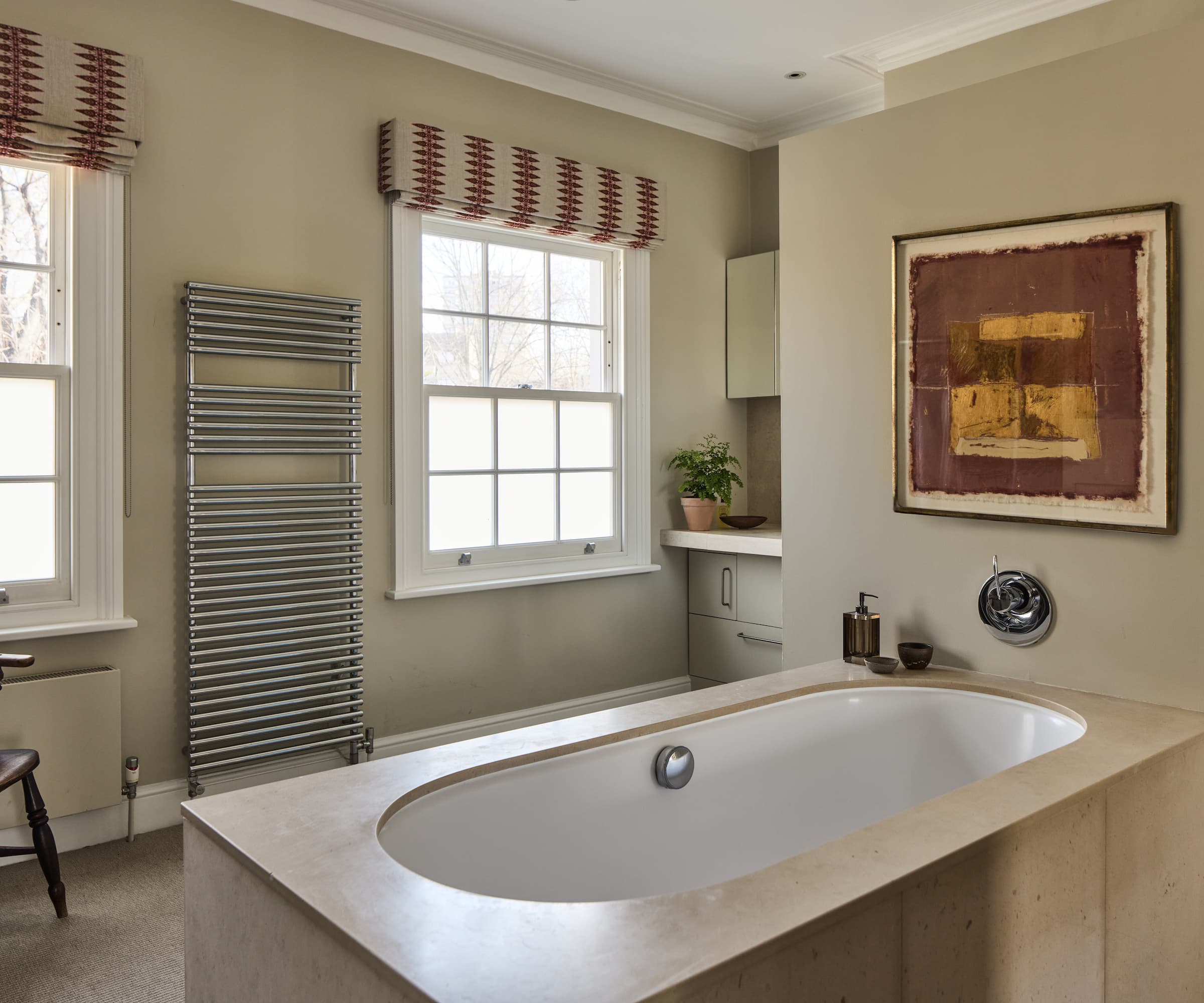 A bath in a square surrounding with a painting on the wall and a wall radiator