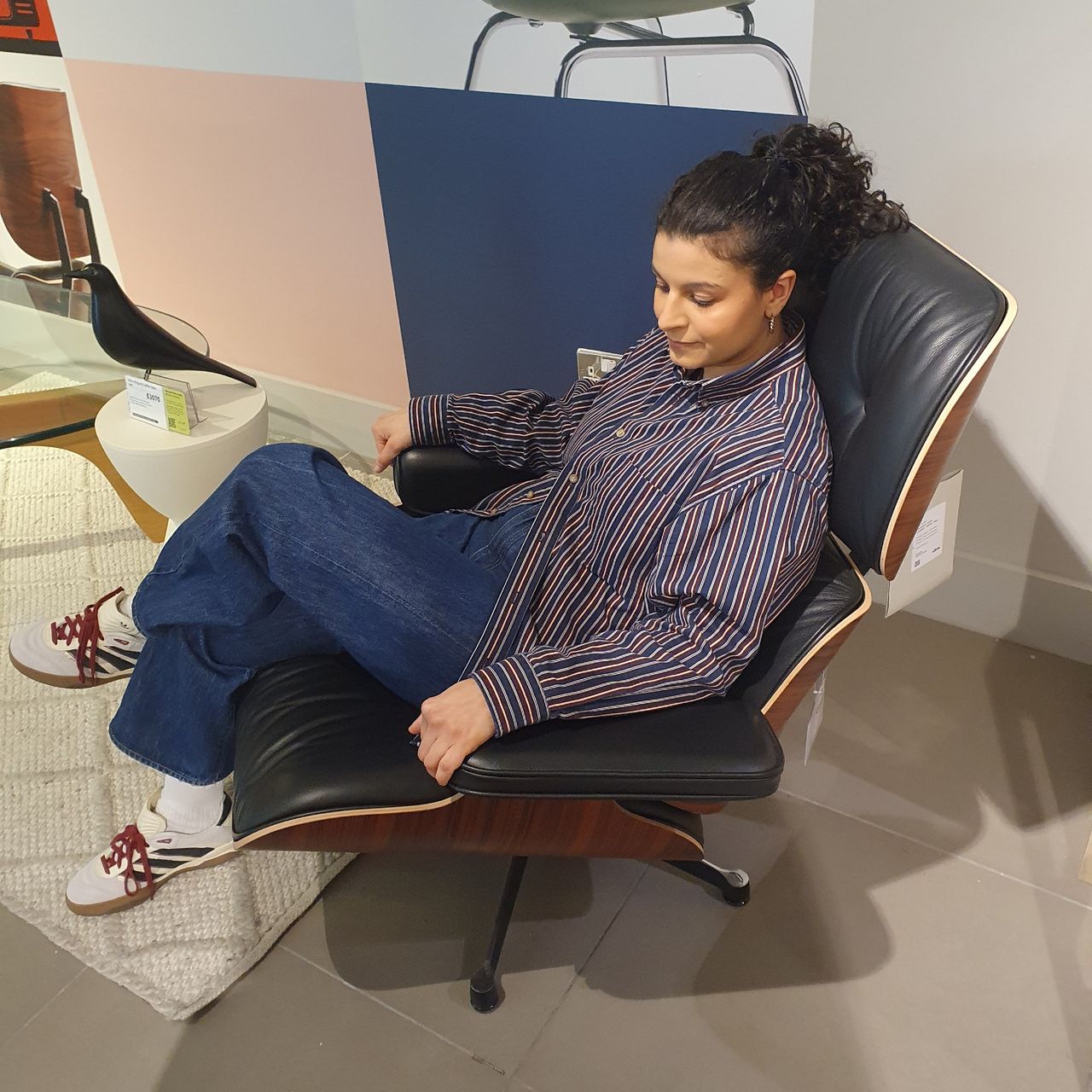 Sara sitting on the Vitra Eames swivel chair in a John Lewis store