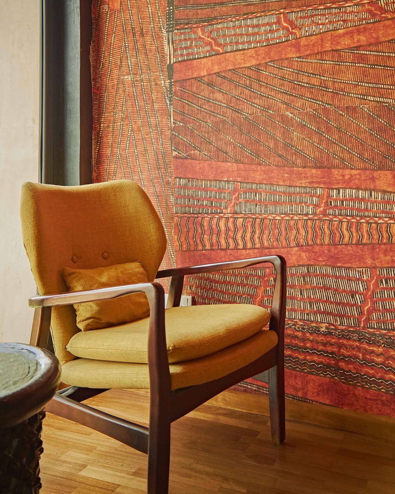 The warm interiors of a private members' club are furnished with woody chairs and coffee tables and soft textiles covered in patterns.