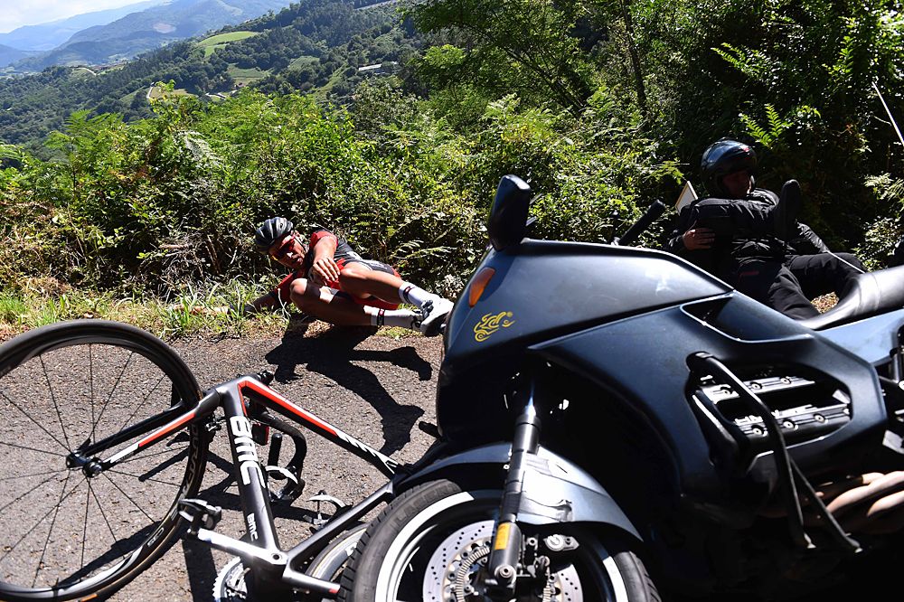 Greg Van Avermaet (BMC) knocked onto the ground after behind hit from behind my a TV motorcycle