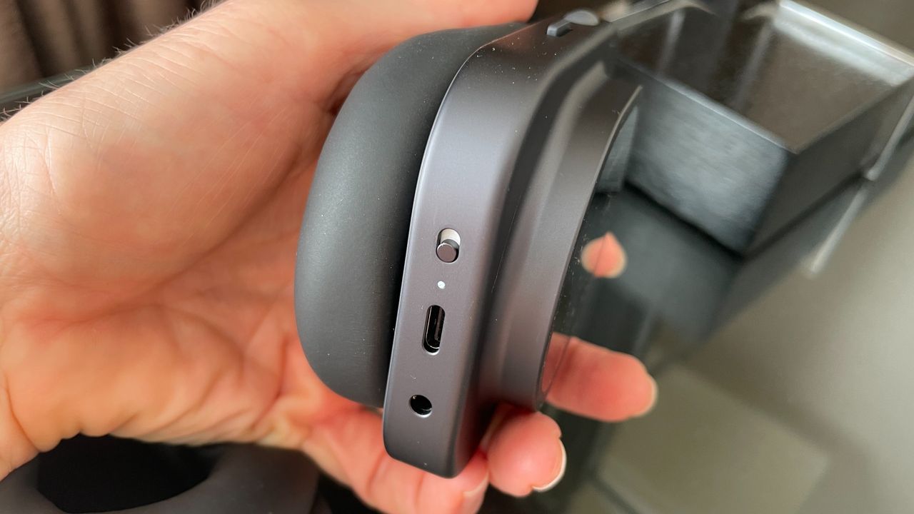 Nothing Headphone (1) Pro with the case on a shiny black and glass table, held in a hand