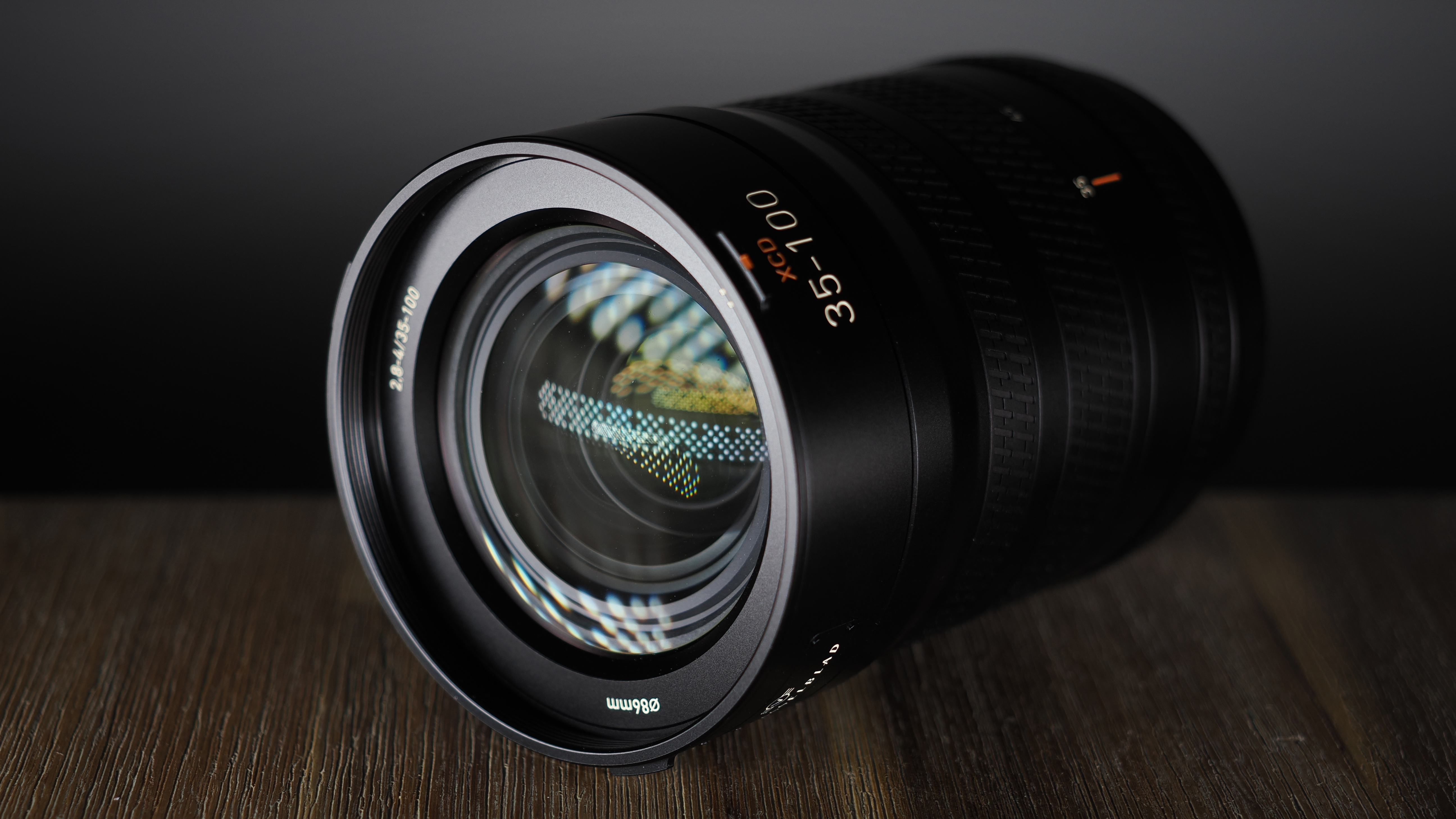 Hasselblad XCD 35-100E lens on a wooden surface in a moodily lit environment