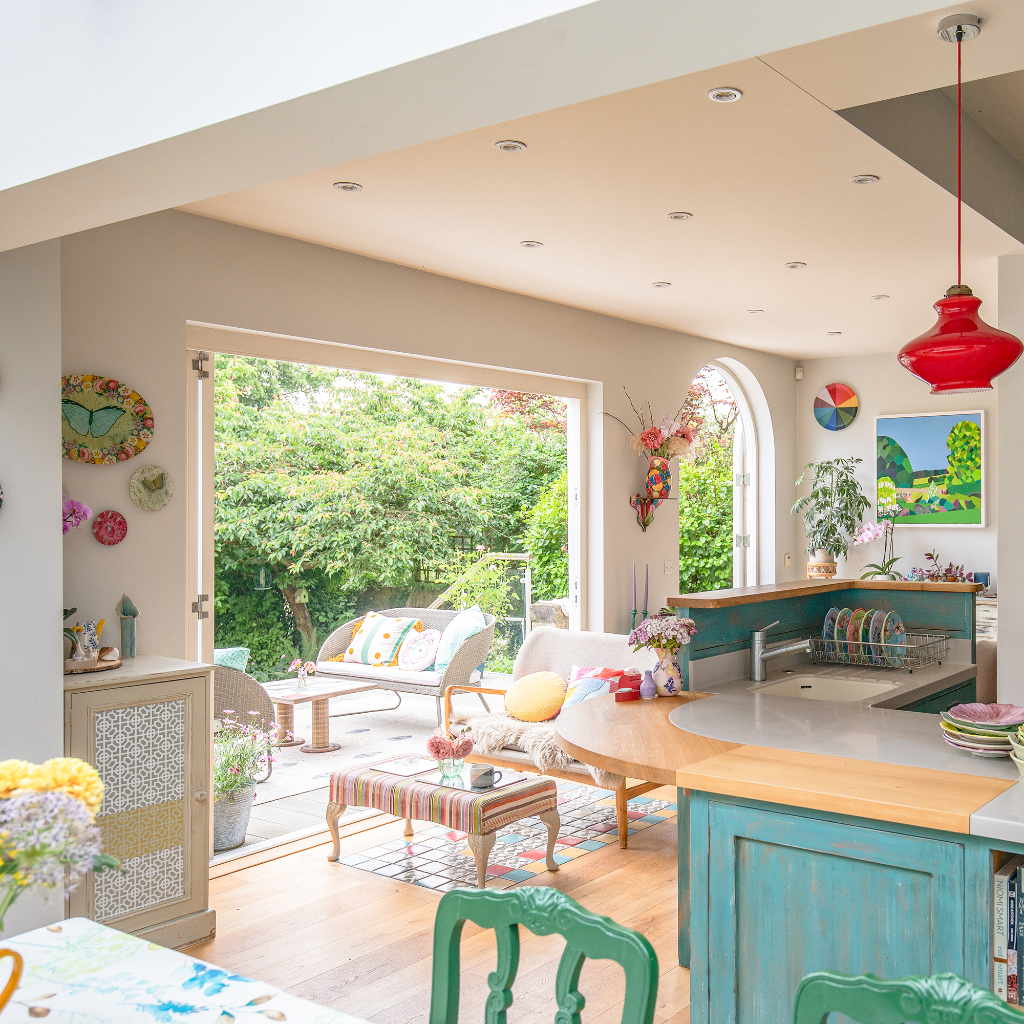 colourful open plan kitchen, diner living space with bifold doors out to garden decking area