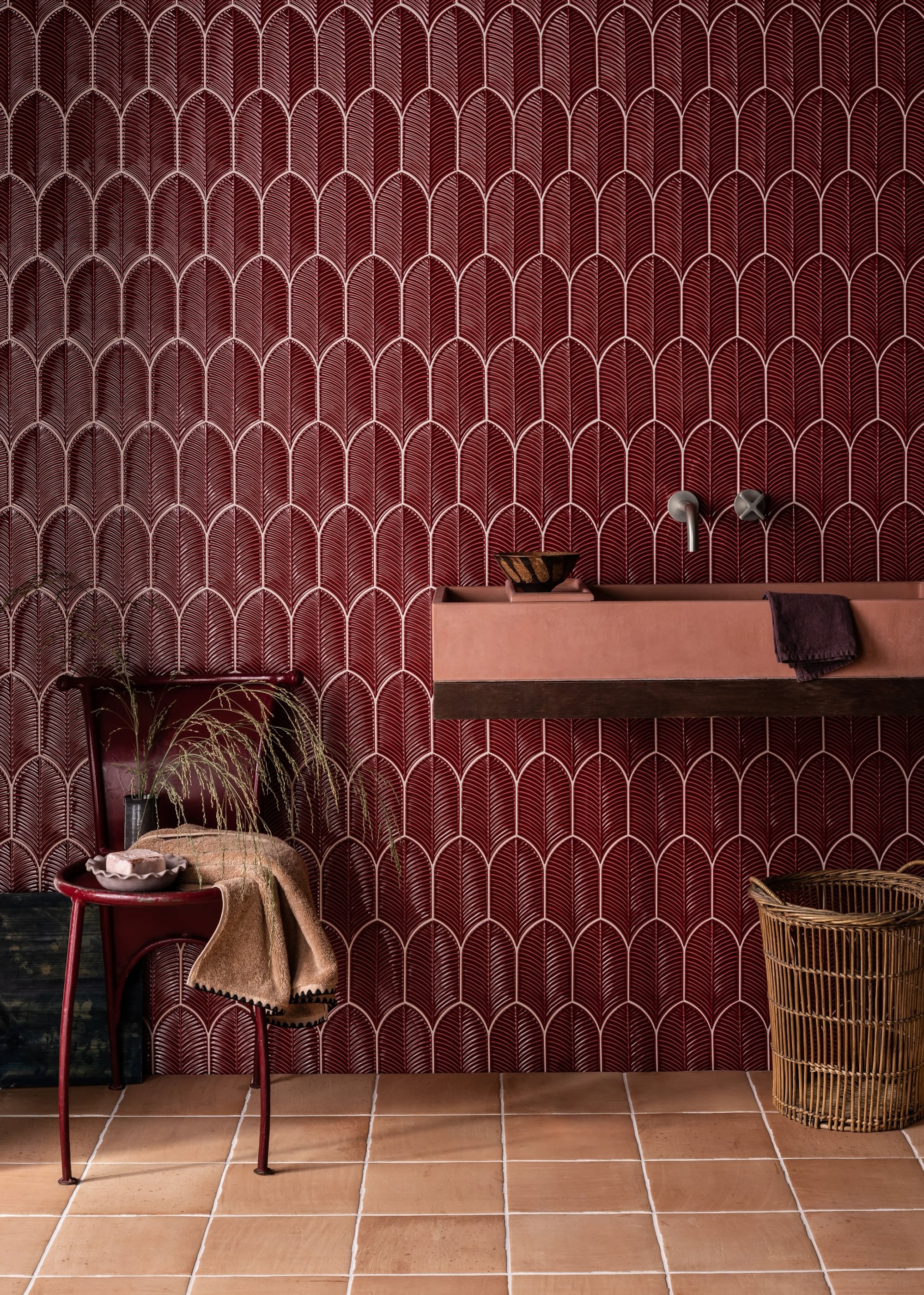 Deep red bathroom wall tiles with terracotta flooring. There is also a chair in the corner of the bathroom.