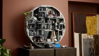 Lego Death Star set, fully constructed, on a wooden side table against a red wall