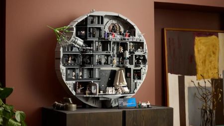 Lego Death Star set, fully constructed, on a wooden side table against a red wall