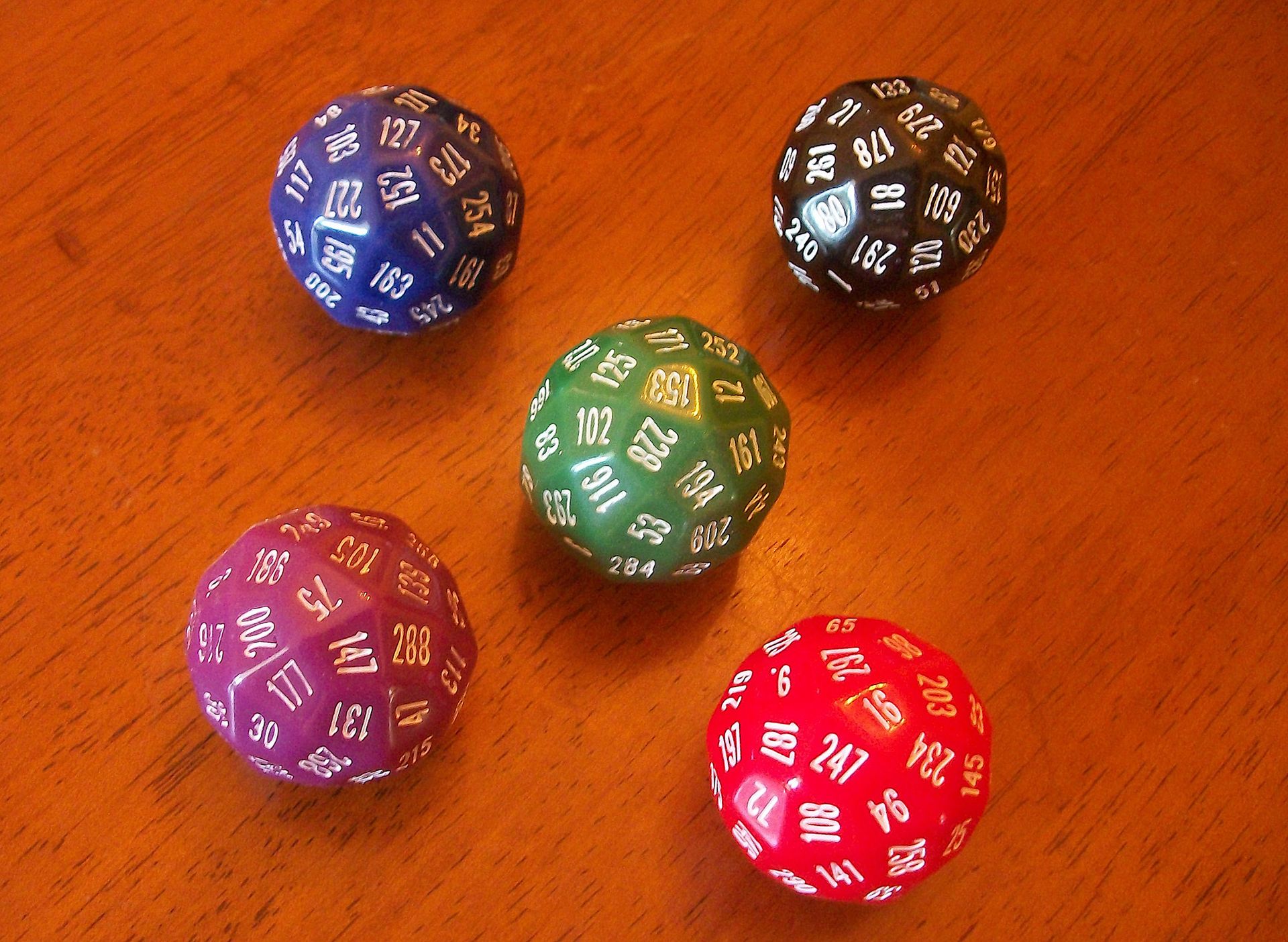 A series of multi-sided colorful dice against a wooden surface