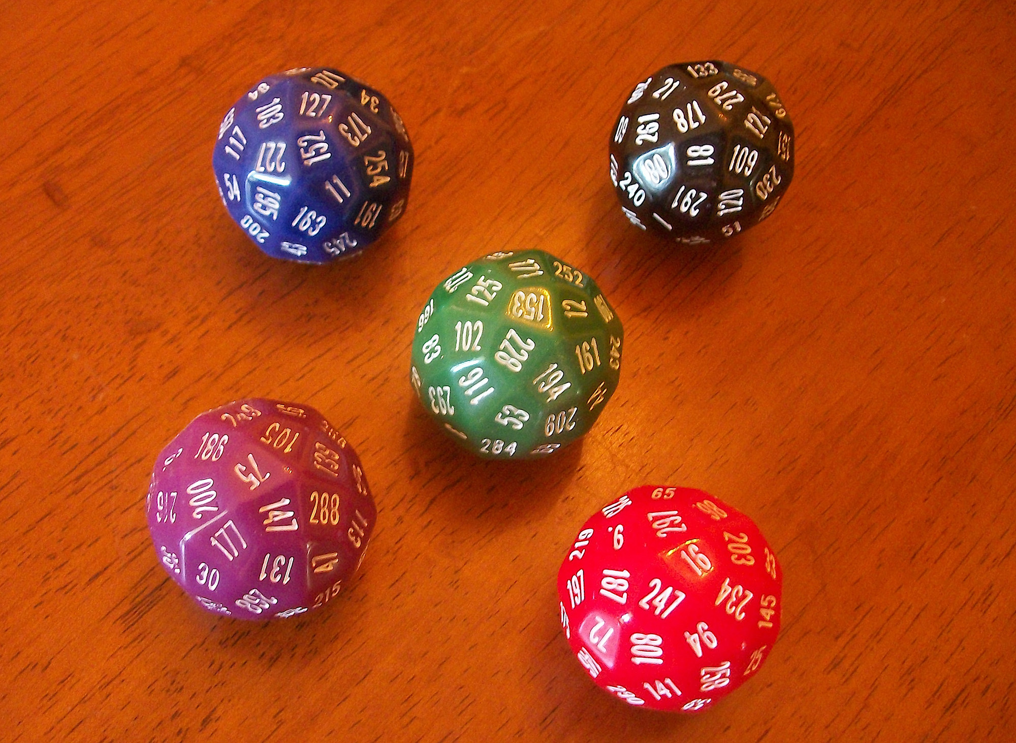 A series of multi-sided colorful dice against a wooden surface